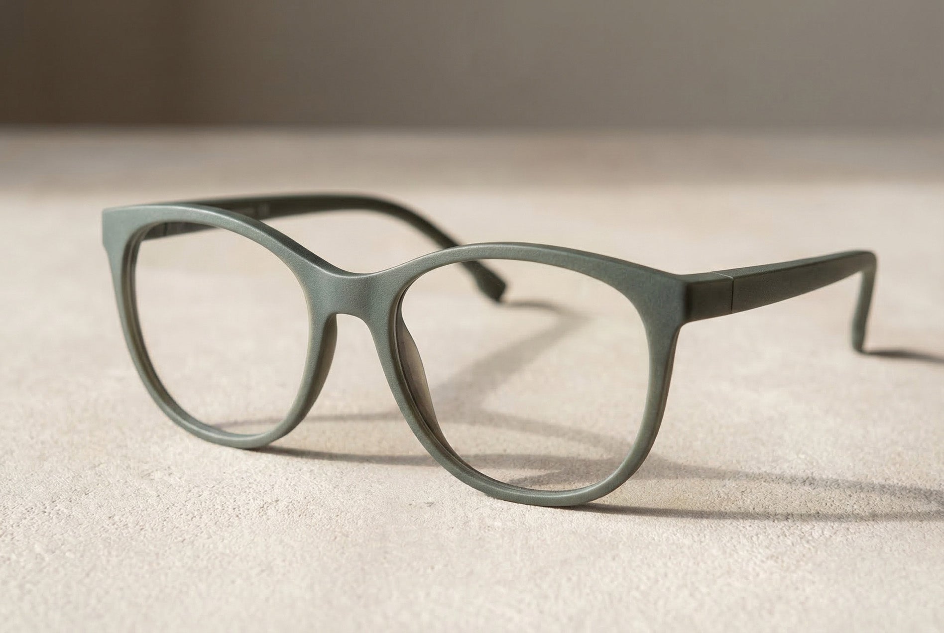 Minimalistische graugrüne 3D-gedruckte Brille mit matter SLS-Oberfläche auf neutralem Studio-Setup