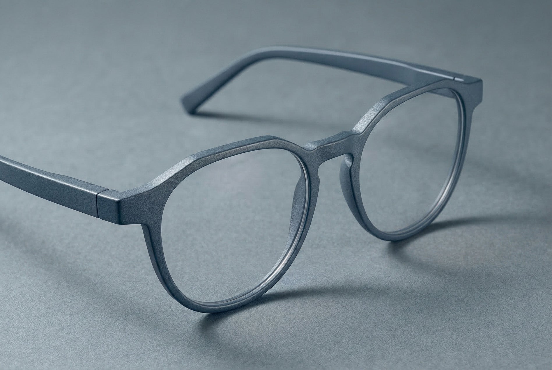 Blaugraue SLS-Brille mit feiner, körniger Oberfläche auf geometrischem Papier-Arrangement im Studio