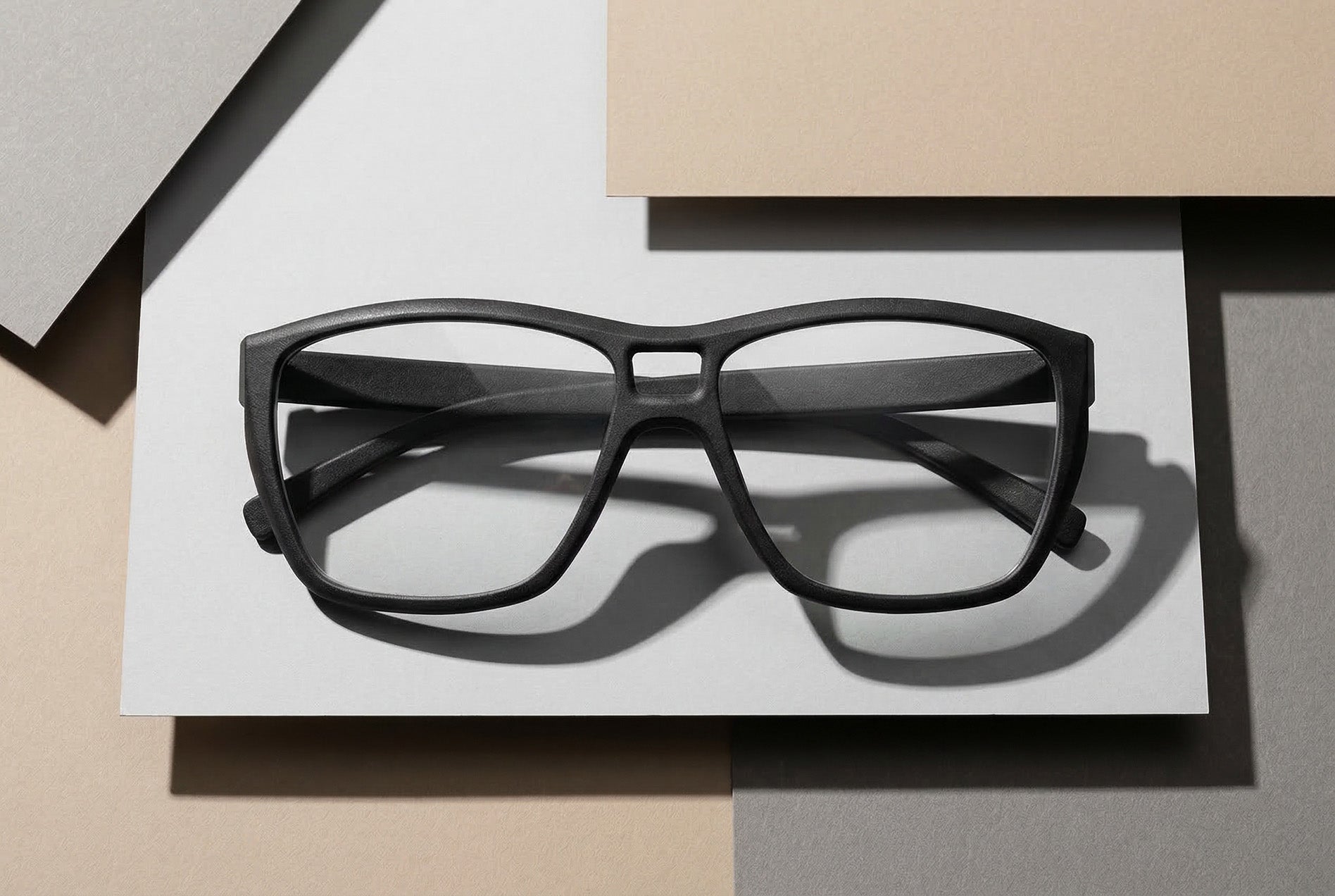 Draufsicht auf schwarze SLS-Brille auf geometrisch angeordneten Papierflächen im Studio